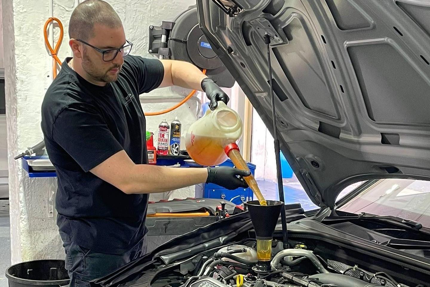 Technicians with a white sedan in the workshop